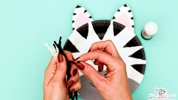 Image showing hands gathering multiple strands of black and white yarn to secure into a bunch.