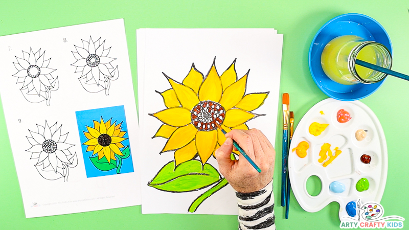 Image showing a hand painting the disc flowers red, brown and black.