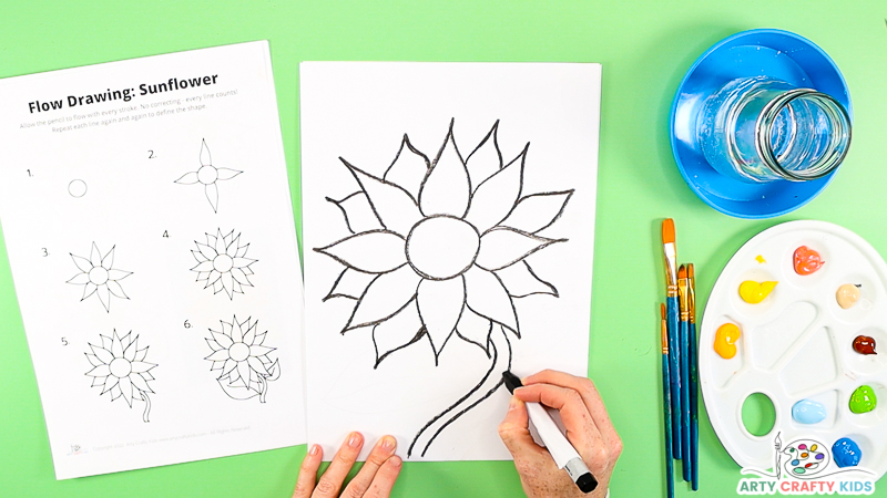 Image showing a complete sunflower bloom and a hand drawing a wavy stem from the flower to the bottom of the page.