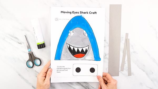 Image featuring a colored in shark template. The shark has been painted blue and gray.