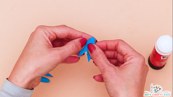 Image showing hands gluing two blue feathers together.