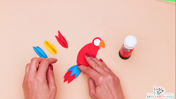 Image showing hands gluing the tail feather onto the body of the parrot.