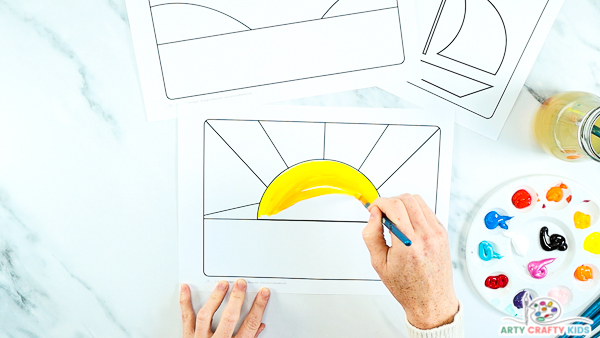 Step one: image showing a hand painting the sun yellow.