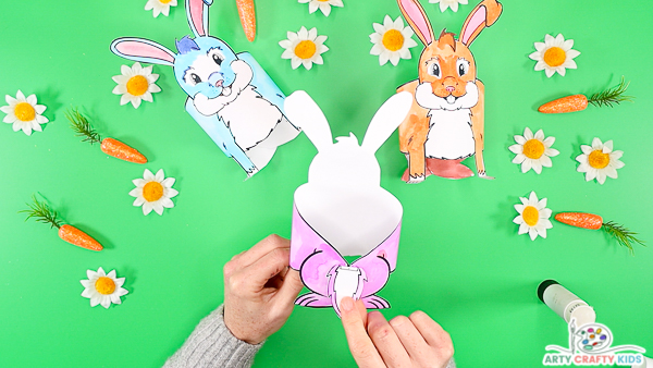 Image featuring hands affixing the bunny template to the bunny's back legs. 