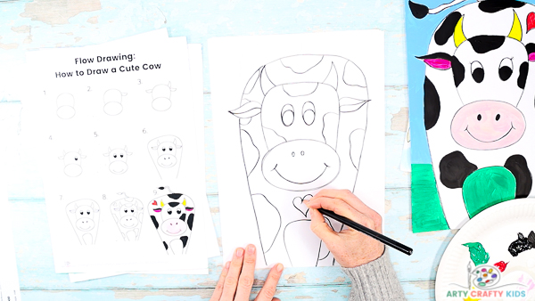 Image illustrating step 8: A hand drawing a heart shape patch on to the  cow with a collection of patches already drawn. 