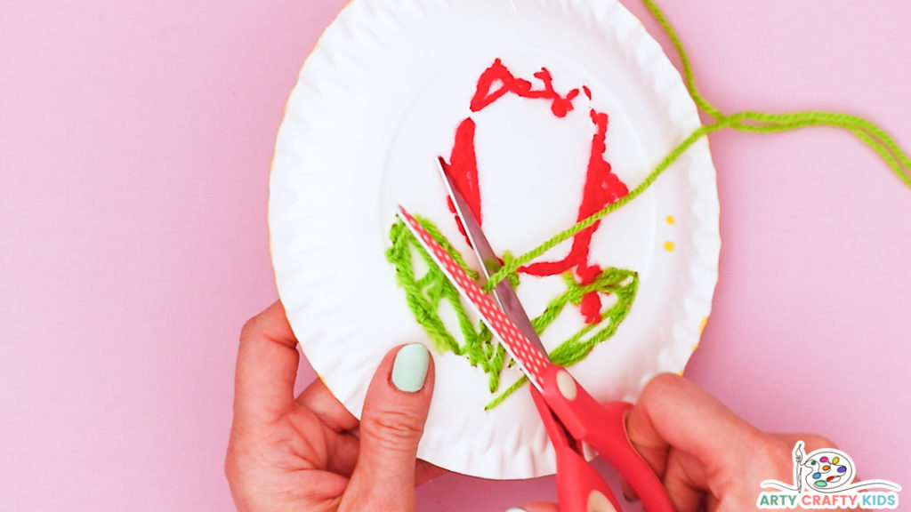 Image showing hands cutting off the excess green yarn from behind the tulip sewing craft.