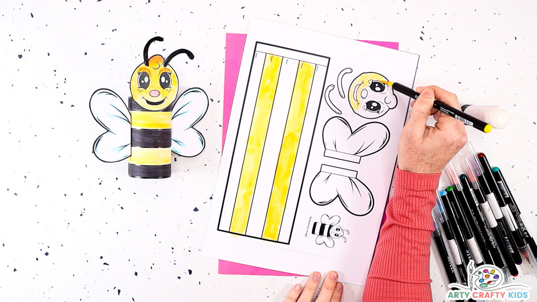 Image featuring a hand coloring in the yellow parts of the bee template.