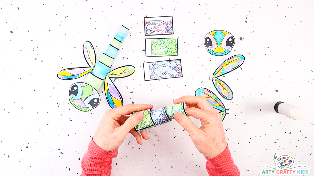 Image featuring a hand joining another segment to the dragonflies body.