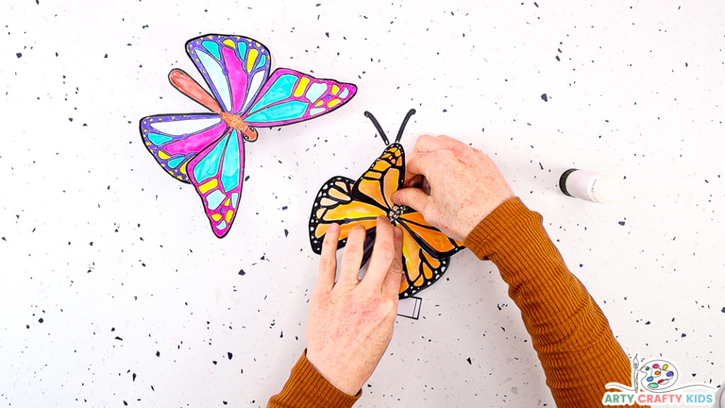 Image featuring a hand securing the last butterfly wing onto its body.