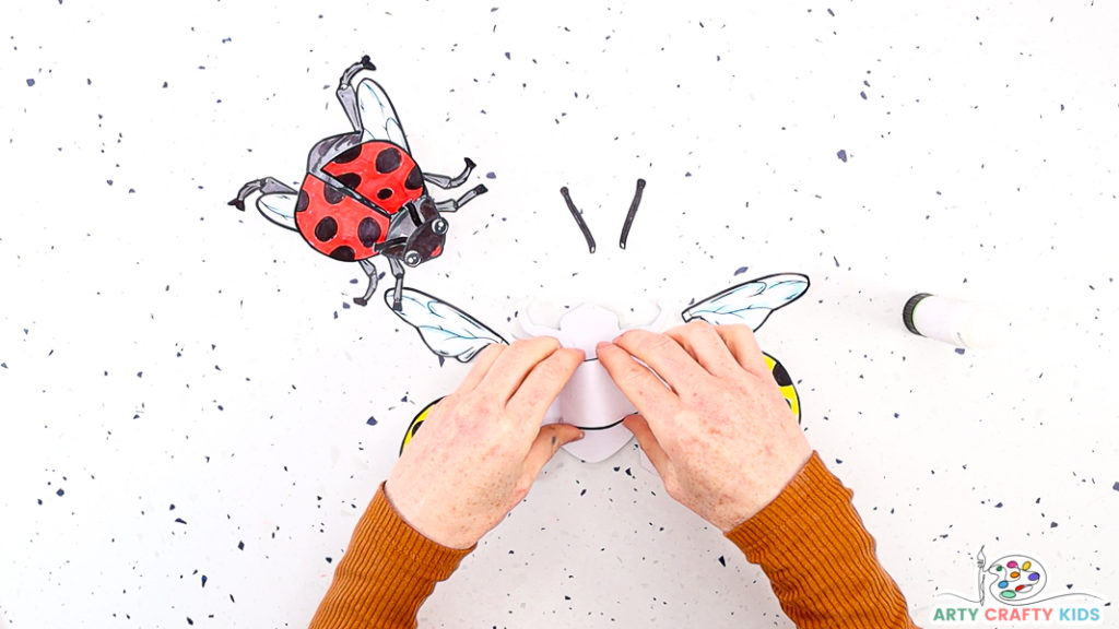 Image features a hand affixing the finger piece onto the back for the ladybug.
