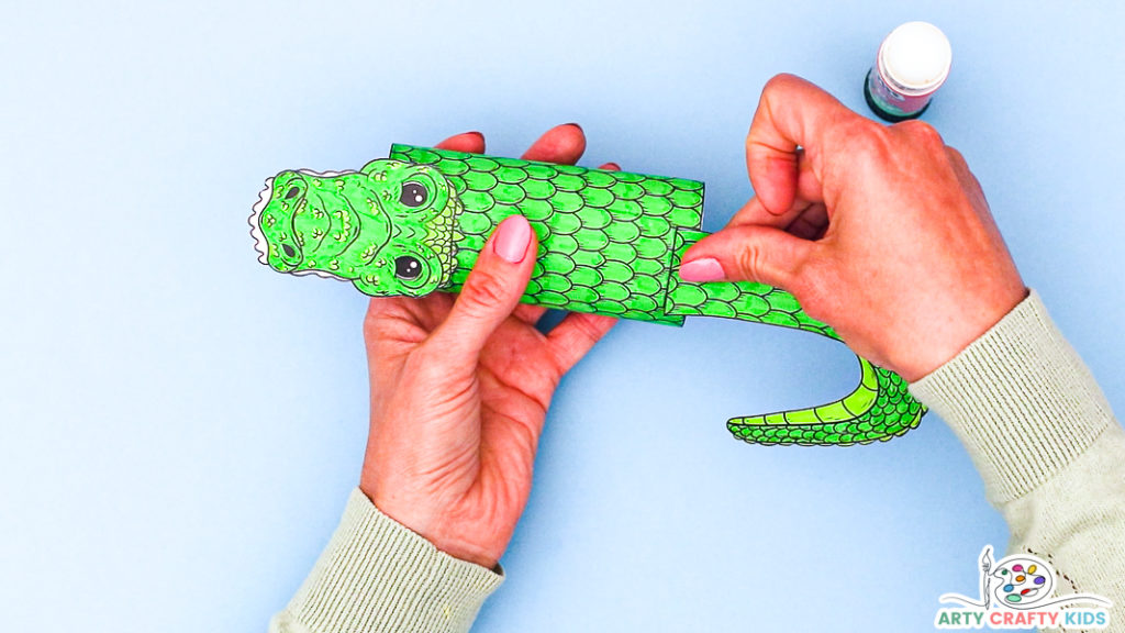 Image of a hand affixing the crocodile's tail to its body.