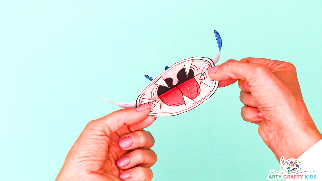 Completed 3D printable shark craft with hands opening the mouth to reveal a big toothy grin, featuring white teeth.