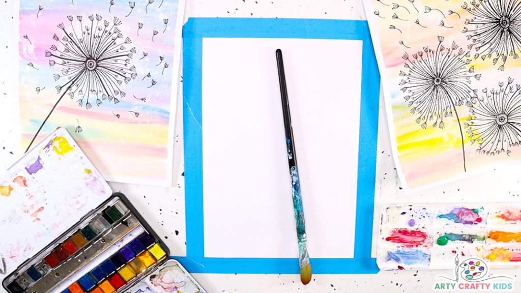 Image features a paint brush resting on a piece of paper taped to the worktop. There's a dandelion painting either side of the paper, with a palette of watercolor paint resting in the bottom left of the image.
