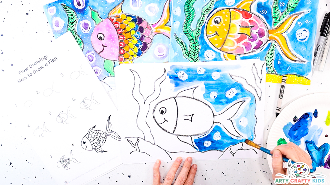 Image featuring a hand applying blue paint to the sea area of the fish picture.