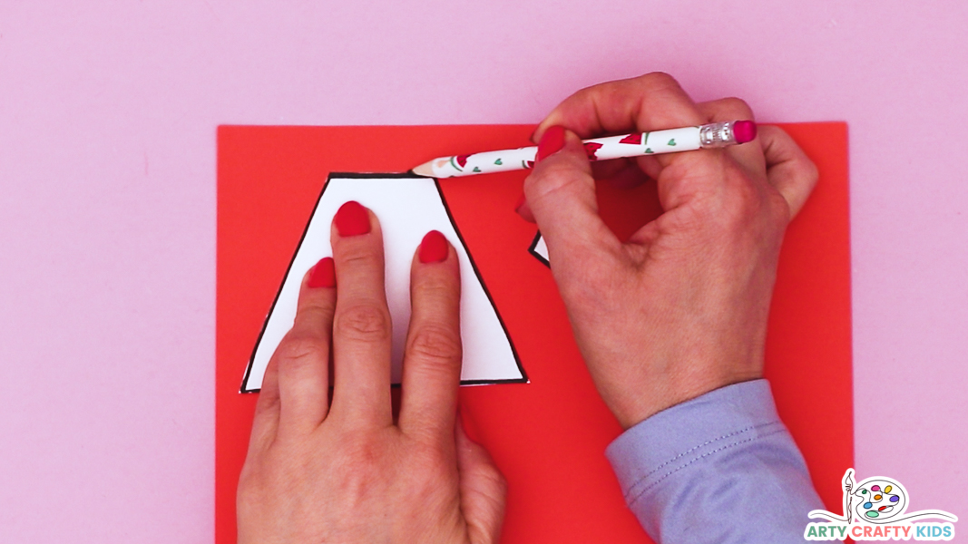 Image featuring a hand tracing a cape and superhero badge onto red paper.