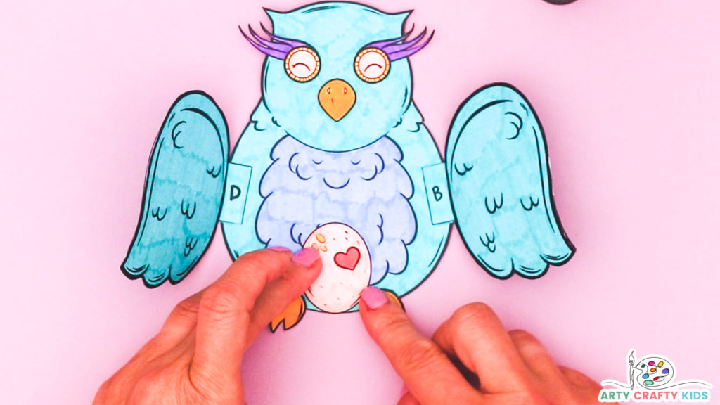 Image of a hand glueing the feet onto the printable owl craft.