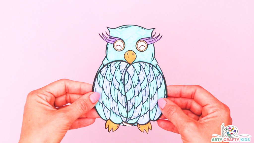 Image of a hand holding a completed owl coloring craft with its wings closed.