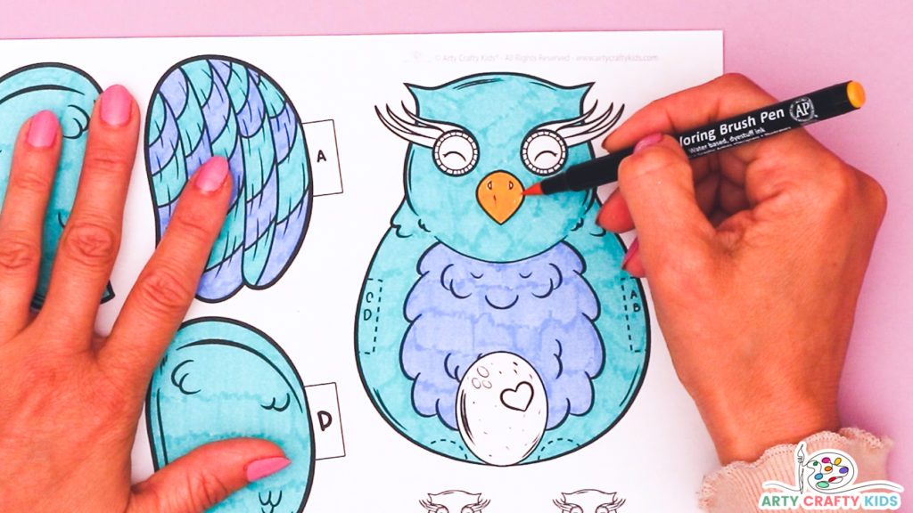 Image featuring a hand coloring in the owl coloring craft with an orange pen for the beak.