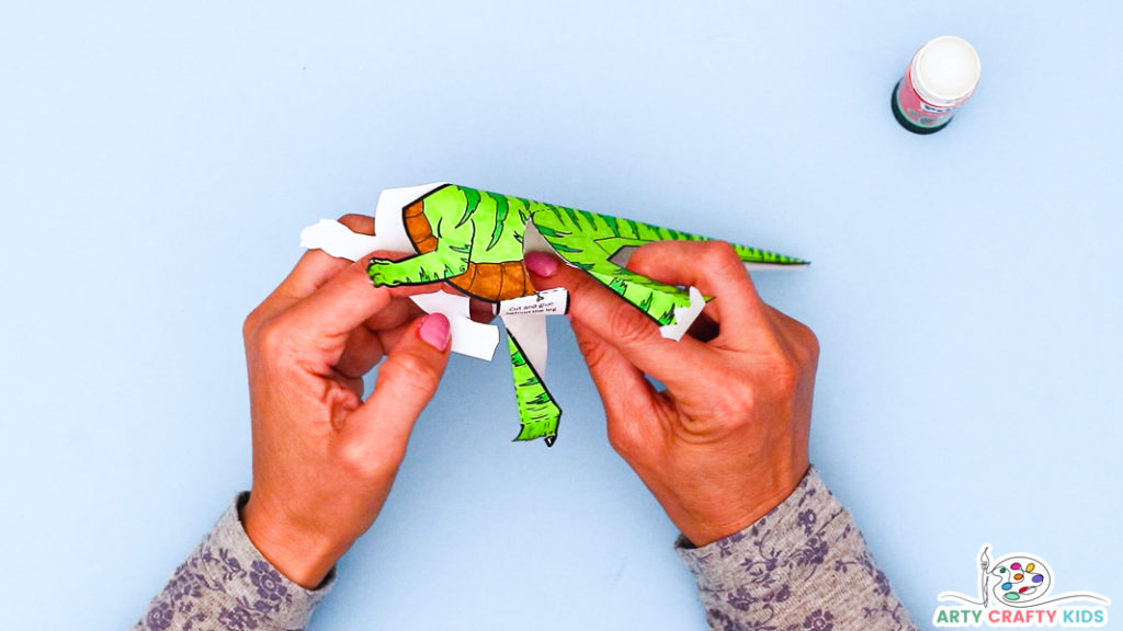 Image featuring a hand bringing the folds to join thus encouraging the dinosaur to assume a standing position.