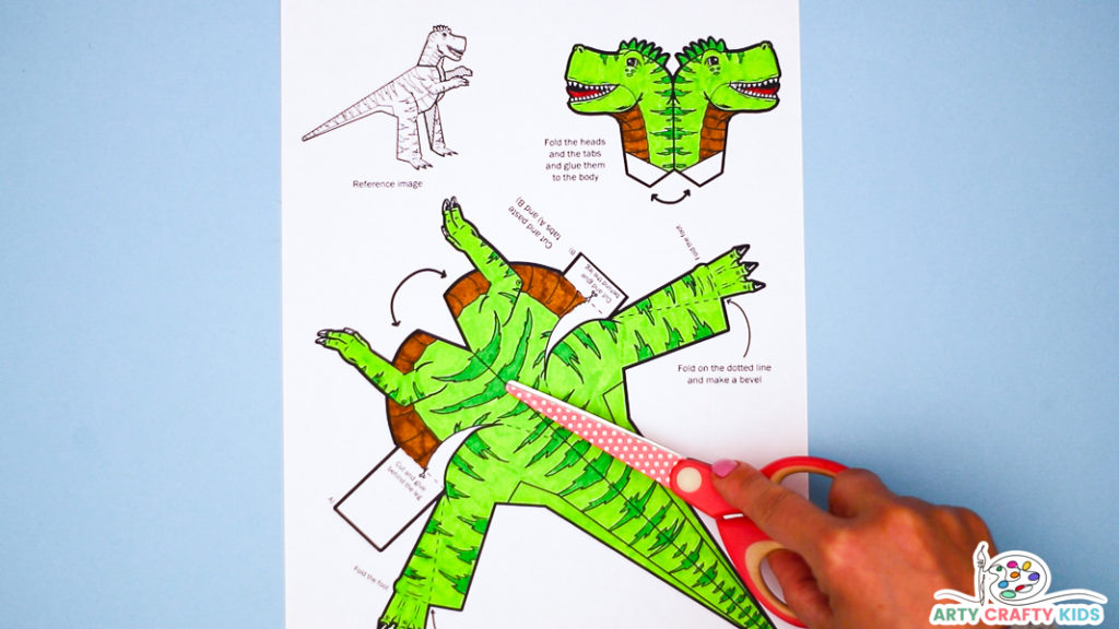 Image featuring a hand pointing to a completed colored in dinosaur template with a pair of scissors.