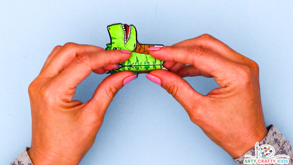Image featuring a pair of hands folding the T'rex's head in half.