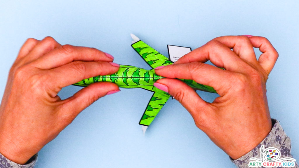 Image featuring a pair of hands creating a fold along the back of the dinosaur.