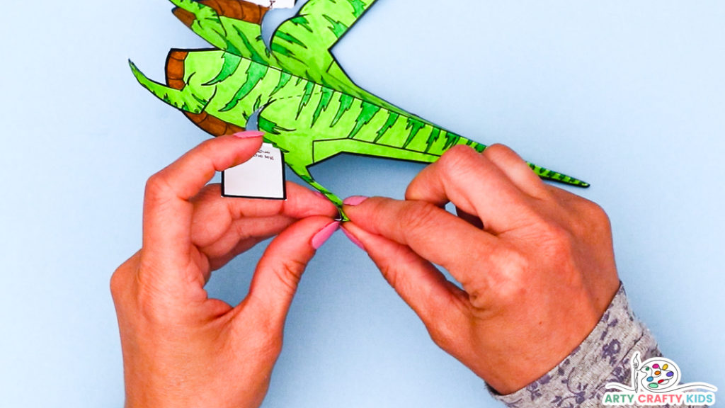 Image featuring a hand folding the dinosaur's feet outwards.