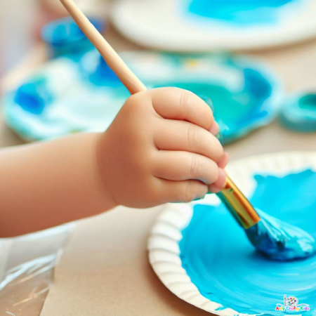 Image of a child's hand painting the paper plate blue to reflect the sky.