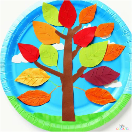 A Autumn tree paper plate craft with painted green grass and blue skies. The tree has a mix of yellow, green, red and brown leaves.