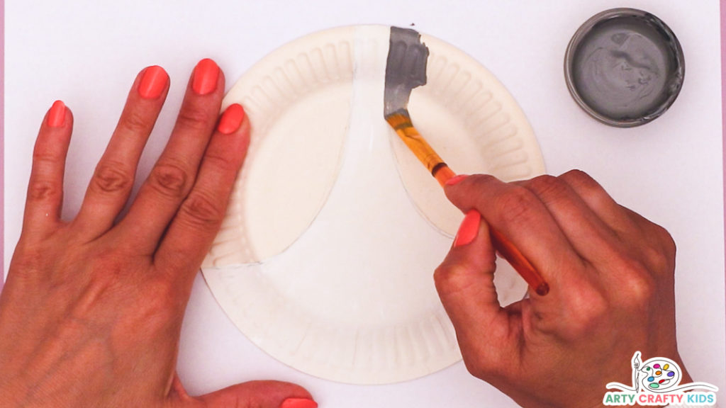 Image featuring a hand painting a paper plate with divided sections for the eyes and mouth.