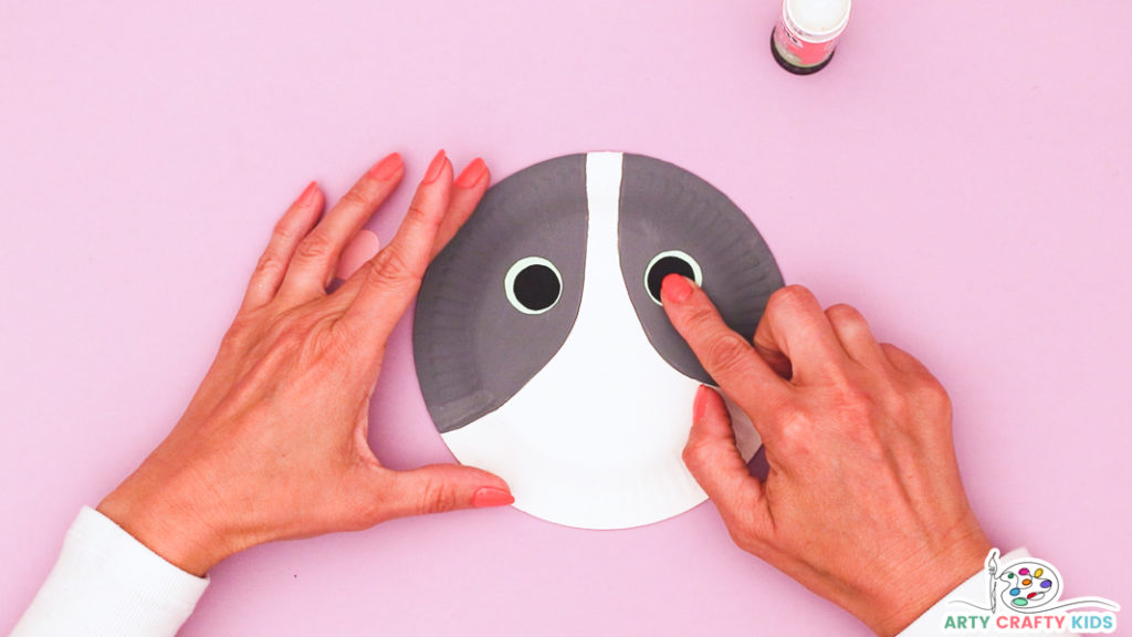 Image of a hand glueing the eyes onto the paper plate.