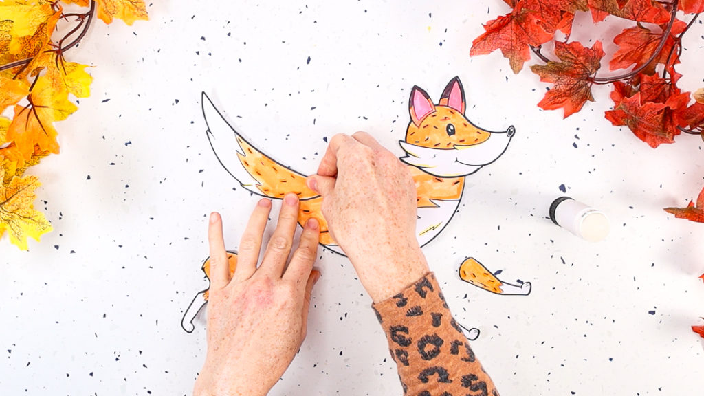 Image featuring a hand glueing the fox's tail onto the body.