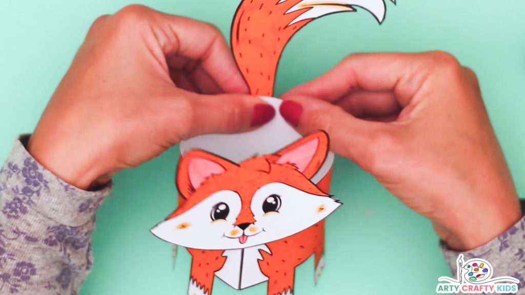Image of a hand affixing the tail piece onto the fox's body. 