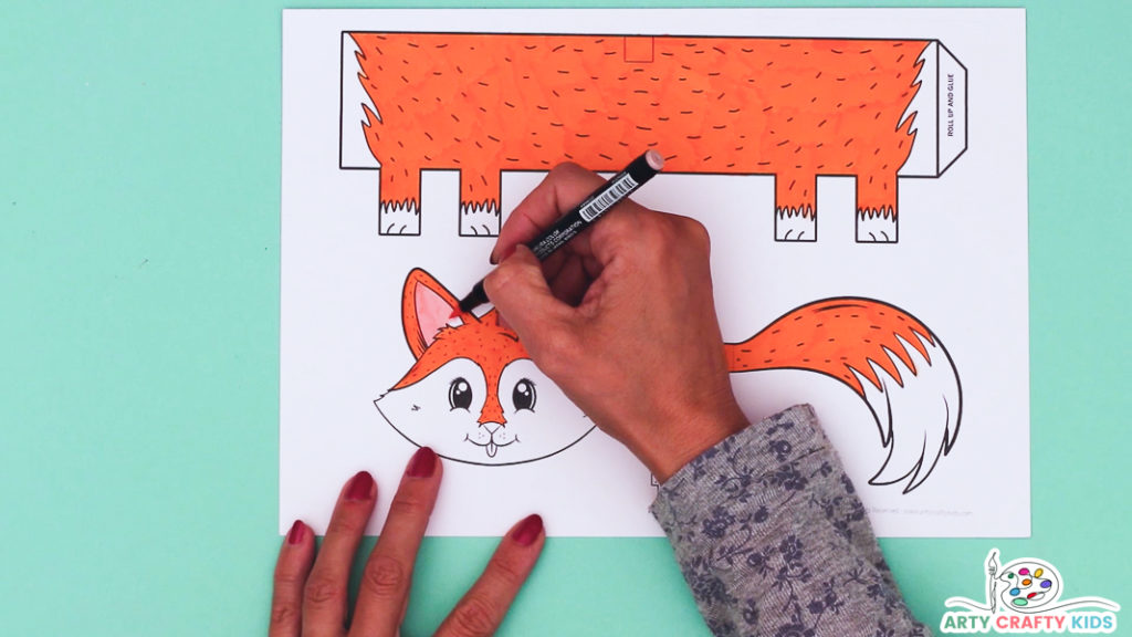 Image featuring a hand carefully coloring in the fox template a bright orange color.