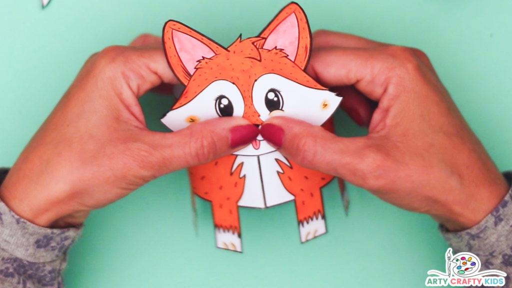 Image of a hand affixing the fox's head to the body. 