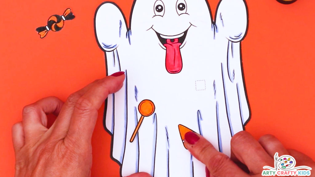 Image featuring a hand affixing the candy elements to the body of the ghost.