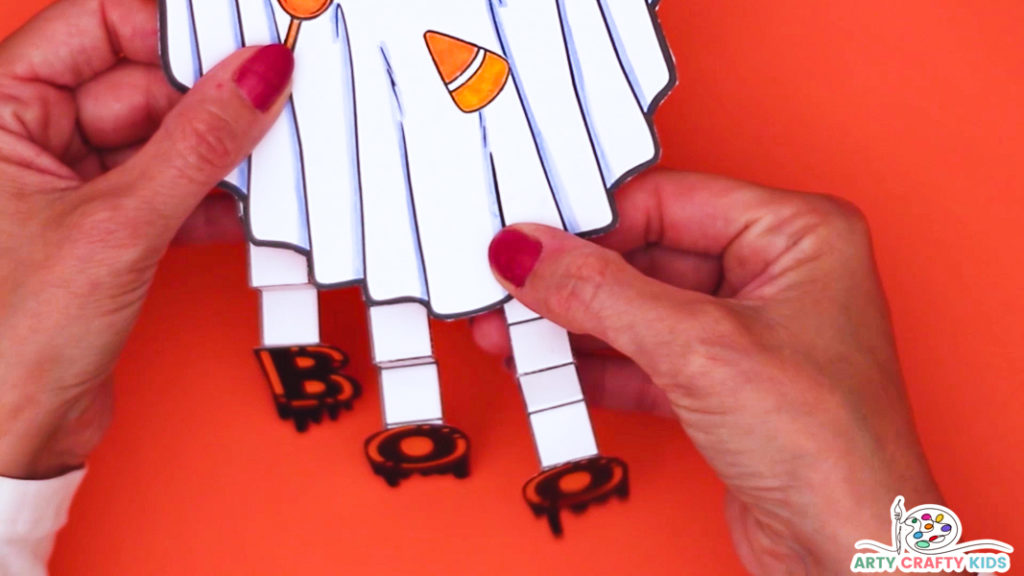 Image featuring a hand glueing the paper strips to the bottom of the ghost.