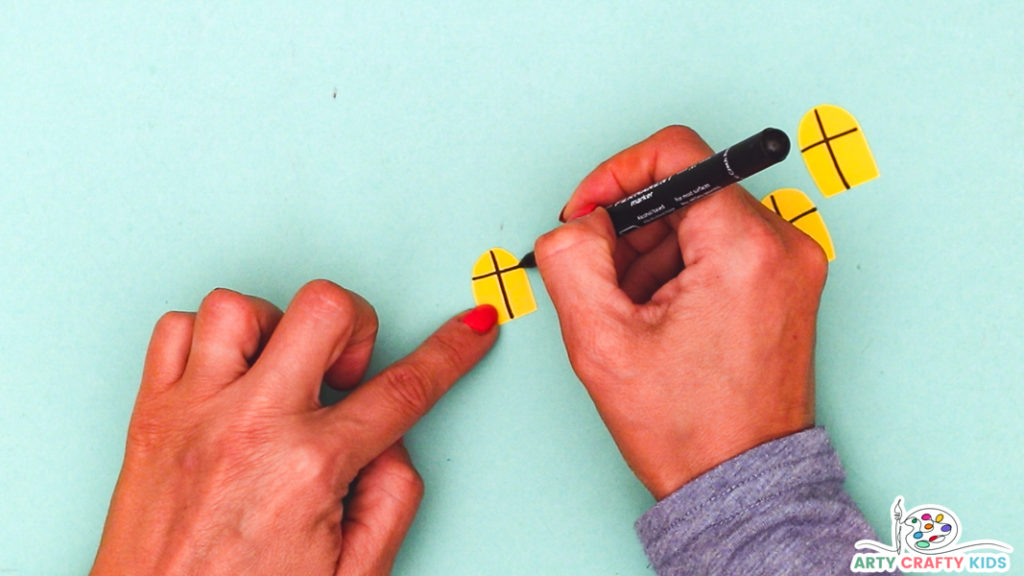 Image featuring a hand drawing crosses onto yellow window pieces of paper.