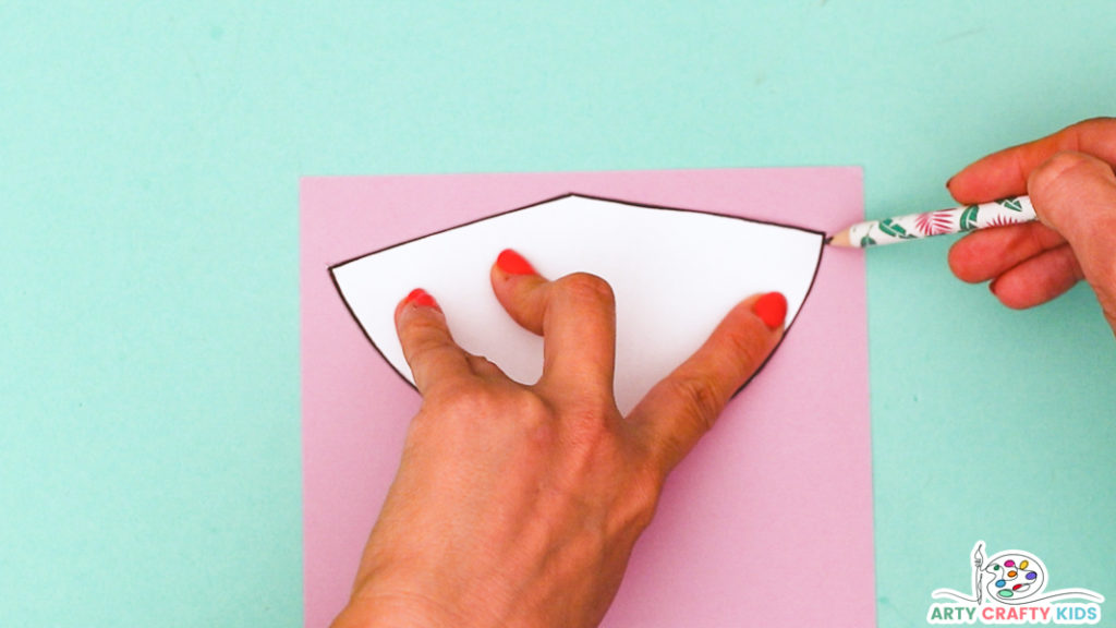 Image featuring a hand tracing the cone shape onto pink paper.