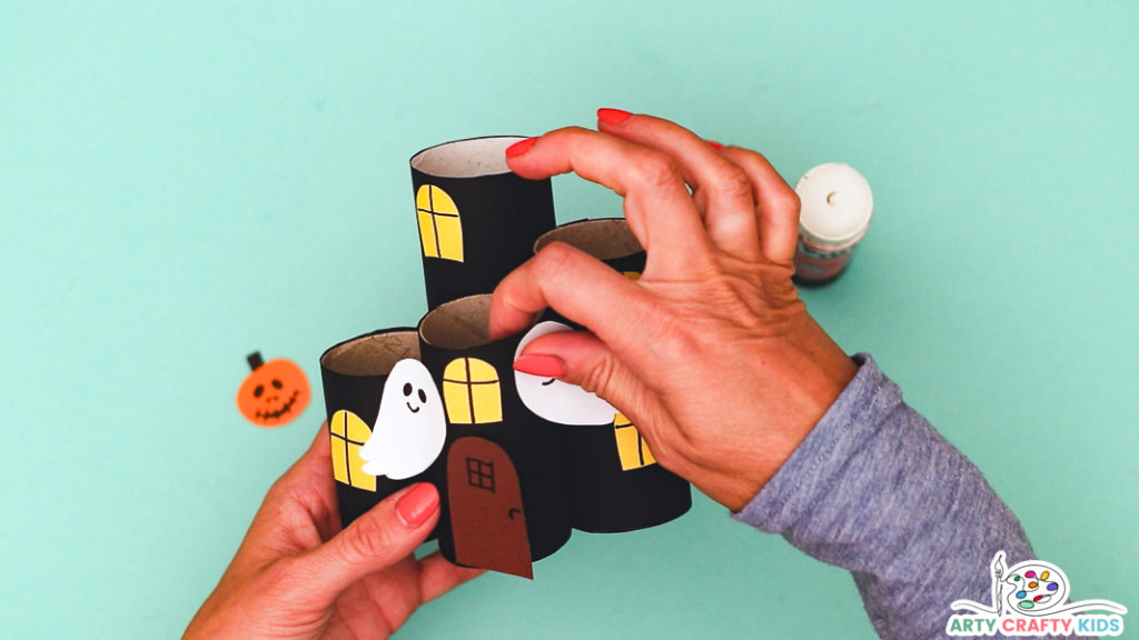 Image featuring a hand glueing the ghosts onto the haunted house.