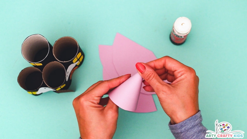 Image of a hand curling the pink paper into cone shapes.