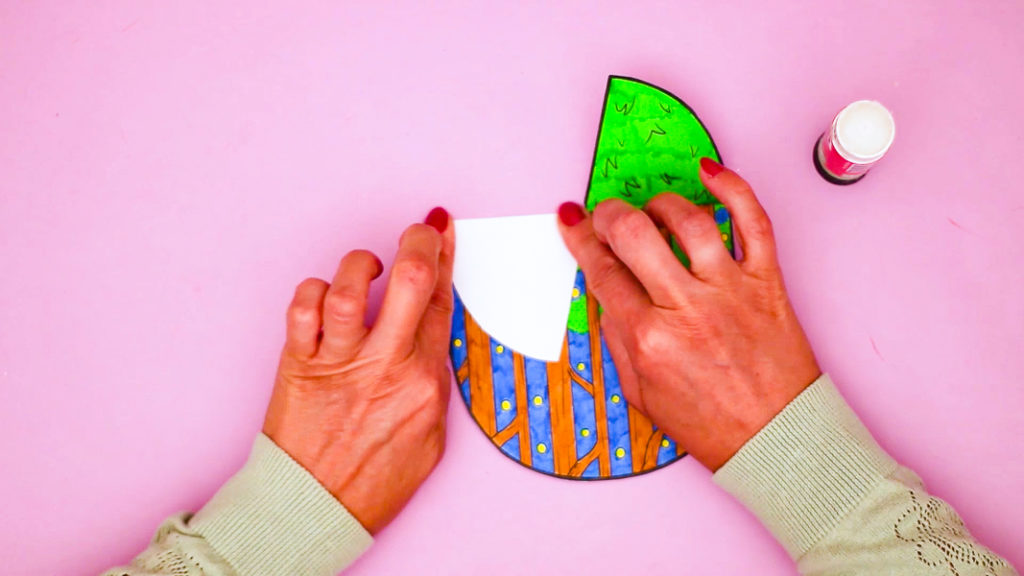 Image of a hand folding the grassy tabs to later enable the pop-up feature of the craft.