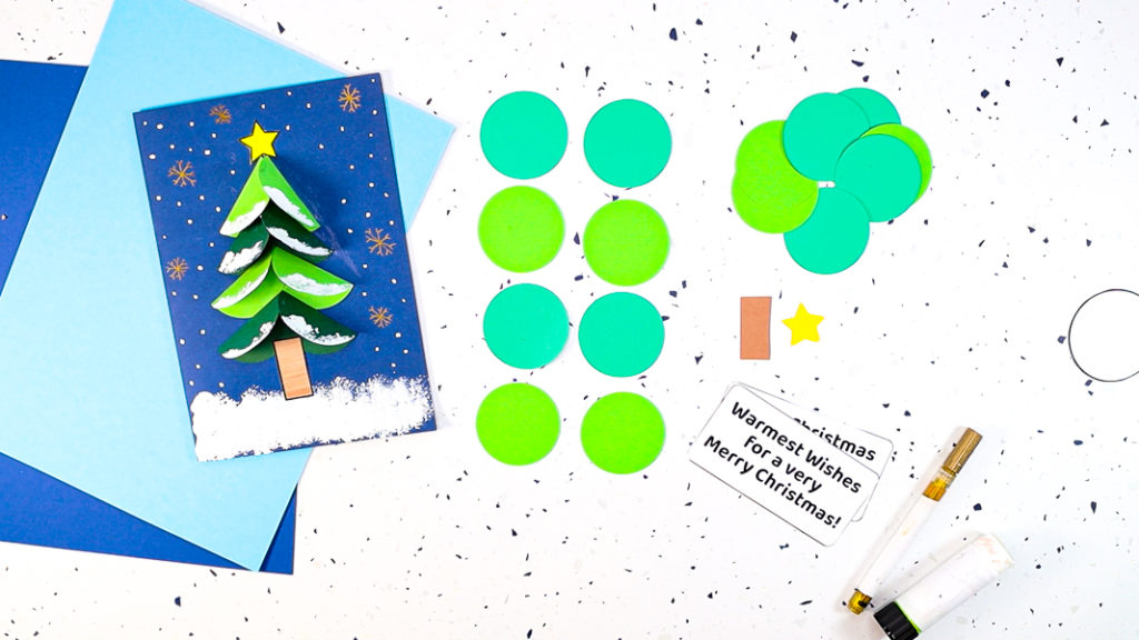 Image featuring 8 green paper circles, a brown tree trunk, star and a completed Christmas tree card.
