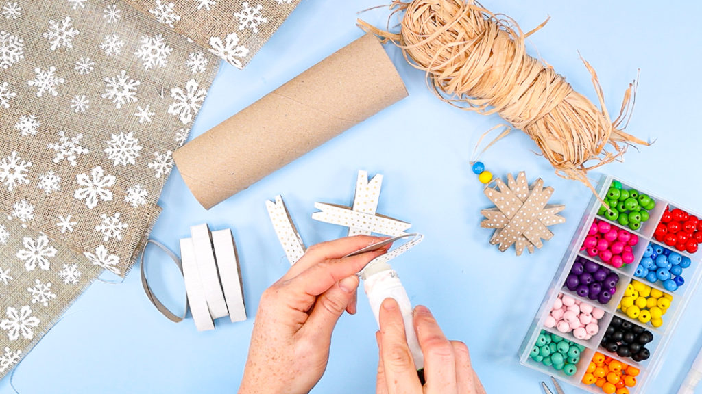 Image showing a hand applying glue to the middle of a snowflake piece.