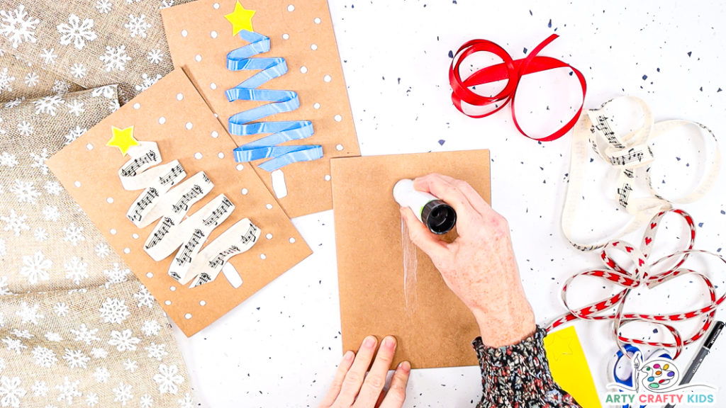 Image showing a hand apply a thick layer of glue to the center of the Christmas card.