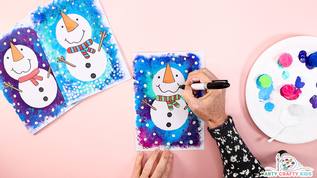 Image of a hand drawing a smiley face and eyes to complete the snowman Christmas card.