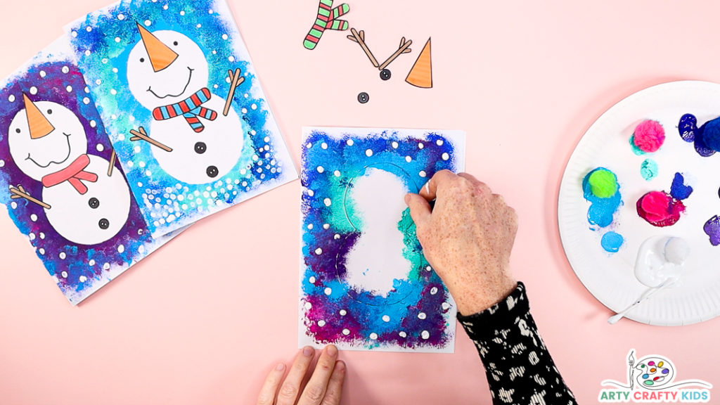 Image of a hand preparing to remove the snowman template to reveal the silhouette.