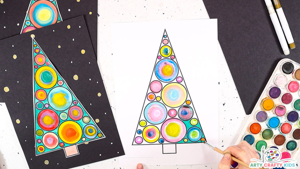 Image of a hand painting the white space within the Christmas tree green .
