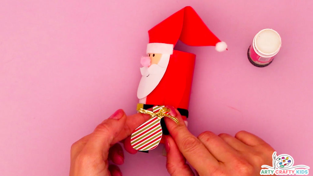 Step 9: Image of a hand affixing the sack of presents onto Santa's arm.