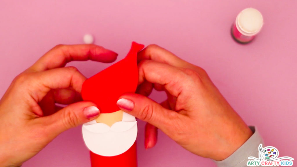 Step 3: Image of a hand affixing a hat onto the Paper Roll Santa Craft.